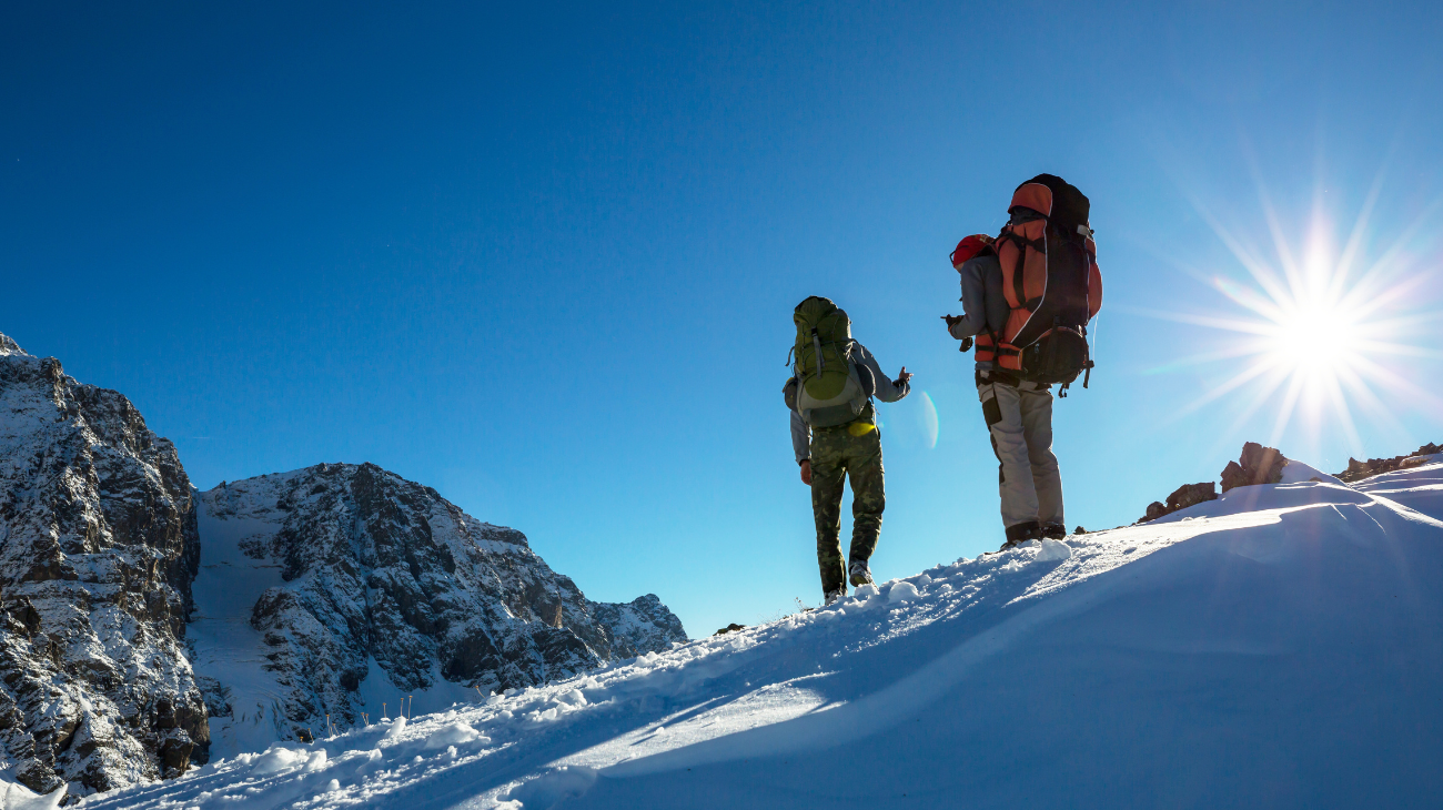 due persone in tuta da sci che fanno turismo montano in inverno